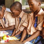 Children focused on writing and studying in a classroom setting, showcasing learning and education.