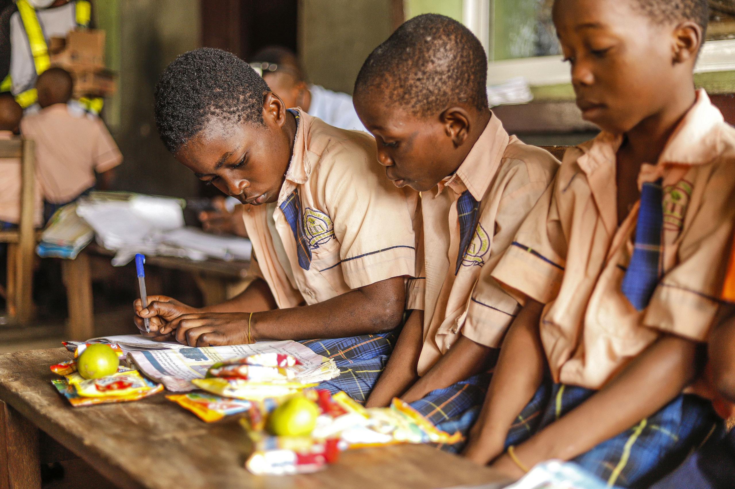 Children focused on writing and studying in a classroom setting, showcasing learning and education.
